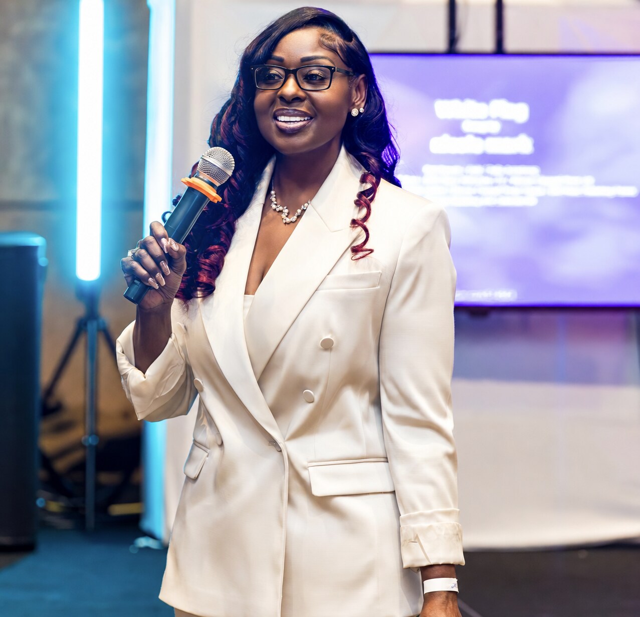 Stacie Phylicia wearing glasses while delivering a keynote with a handheld microphone